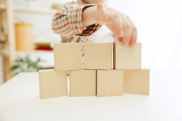 Image showing Little child sitting on the floor. Pretty boy palying with wooden cubes at home