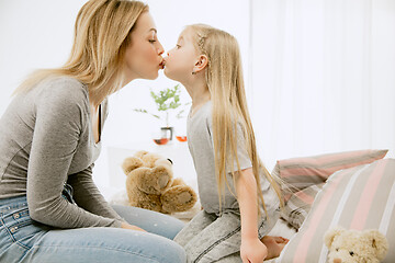 Image showing Young mother and her little daughter hugging and kissing on bed