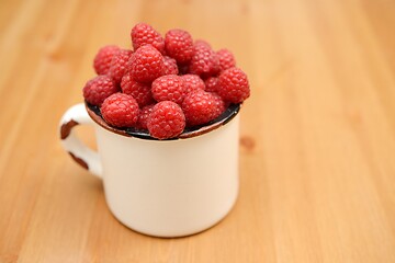 Image showing large ripe raspberries in a mug 