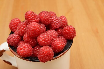 Image showing large ripe raspberries in a mug 