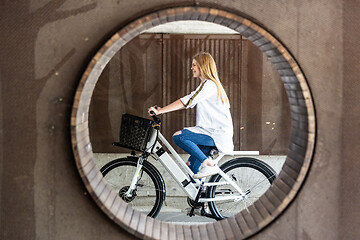 Image showing Casual caucasian teenager riding urban electric bicycle in urban environment. Urban mobility concept