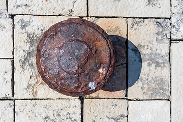 Image showing Old rusted mooring bollard on old stone pier background