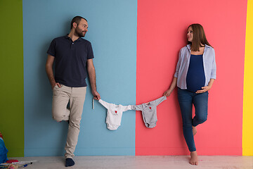 Image showing young couple holding baby bodysuits