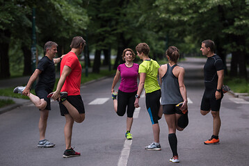 Image showing runners team warming up and stretching before morning training