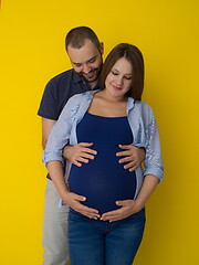 Image showing pregnant couple  isolated over yellow background