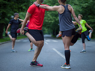 Image showing runners team warming up and stretching before morning training