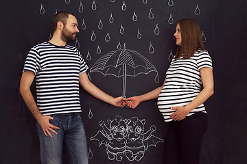 Image showing pregnant couple drawing their imaginations on chalk board