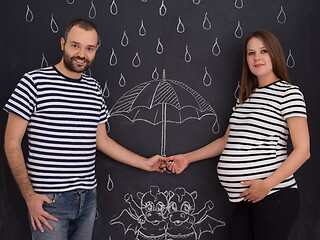 Image showing pregnant couple drawing their imaginations on chalk board