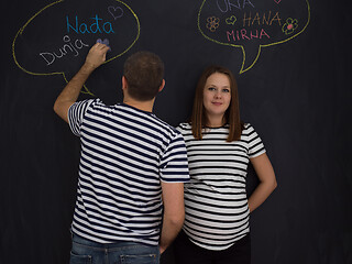 Image showing pregnant couple writing on a black chalkboard