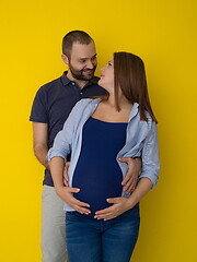 Image showing pregnant couple  isolated over yellow background