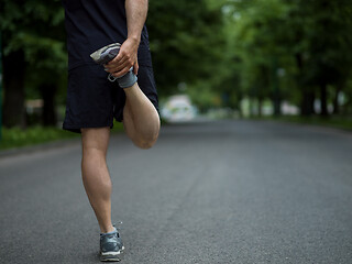 Image showing male runner warming up and stretching before morning training