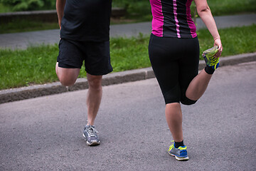 Image showing runners team warming up and stretching before morning training