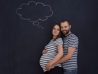 Image showing pregnant couple posing against black chalk drawing board