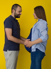 Image showing pregnant couple  isolated over yellow background