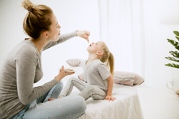 Image showing Young mother and her little daughter hugging and kissing on bed