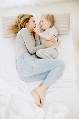 Image showing Young mother and her little daughter hugging and kissing on bed