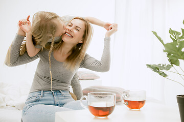 Image showing Young mother and her little daughter hugging and kissing on bed