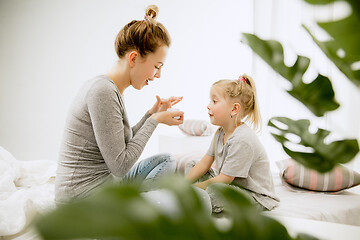 Image showing Young mother and her little daughter hugging and kissing on bed