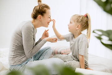 Image showing Young mother and her little daughter hugging and kissing on bed