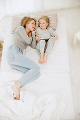 Image showing Young mother and her little daughter hugging and kissing on bed