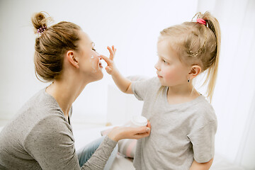 Image showing Young mother and her little daughter hugging and kissing on bed