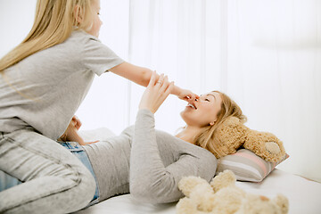 Image showing Young mother and her little daughter hugging and kissing on bed