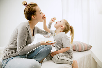 Image showing Young mother and her little daughter hugging and kissing on bed