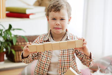 Image showing Little child sitting on the floor. Pretty boy palying with wooden cubes at home