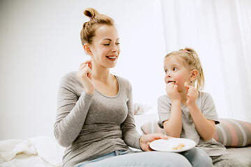 Image showing Young mother and her little daughter hugging and kissing on bed