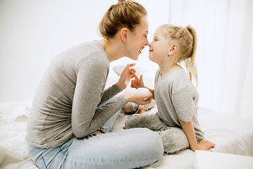 Image showing Young mother and her little daughter hugging and kissing on bed