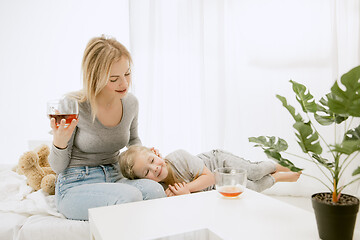 Image showing Young mother and her little daughter hugging and kissing on bed