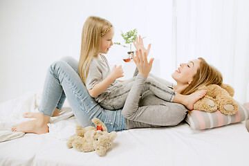 Image showing Young mother and her little daughter hugging and kissing on bed