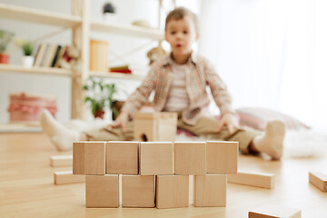 Image showing Little child sitting on the floor. Pretty boy palying with wooden cubes at home