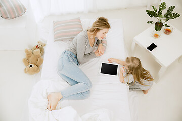 Image showing Young mother and her little daughter hugging and kissing on bed