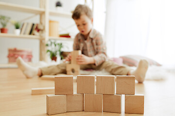 Image showing Little child sitting on the floor. Pretty boy palying with wooden cubes at home