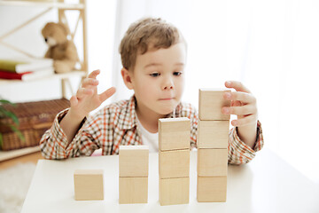 Image showing Little child sitting on the floor. Pretty boy palying with wooden cubes at home