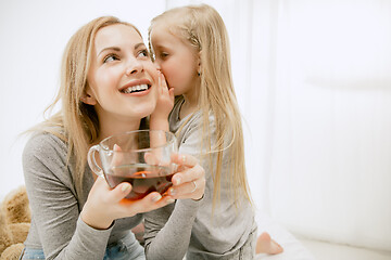 Image showing Young mother and her little daughter hugging and kissing on bed