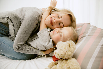 Image showing Young mother and her little daughter hugging and kissing on bed