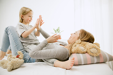 Image showing Young mother and her little daughter hugging and kissing on bed