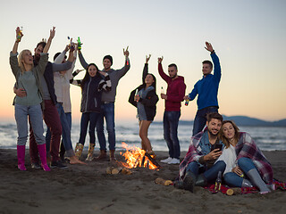 Image showing Couple enjoying bonfire with friends on beach