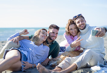 Image showing Group of friends having fun on beach during autumn day