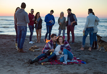 Image showing Couple enjoying with friends at sunset on the beach