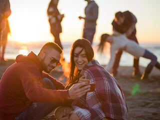 Image showing Couple enjoying bonfire with friends on beach