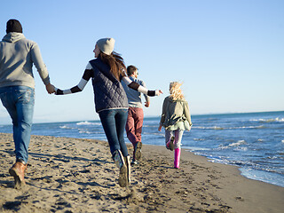 Image showing Group of friends running on beach during autumn day