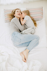 Image showing Young mother and her little daughter hugging and kissing on bed