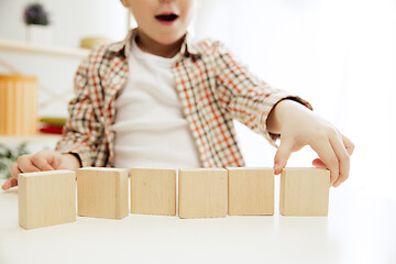 Image showing Little child sitting on the floor. Pretty boy palying with wooden cubes at home