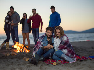 Image showing Couple enjoying bonfire with friends on beach