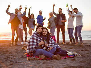 Image showing Couple enjoying with friends at sunset on the beach