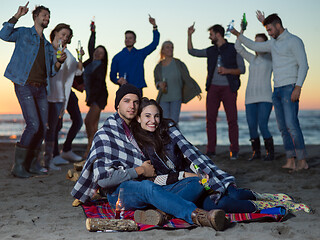 Image showing Couple enjoying with friends at sunset on the beach