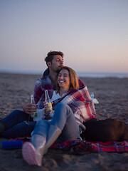 Image showing Loving Young Couple Sitting On The Beach beside Campfire drinkin